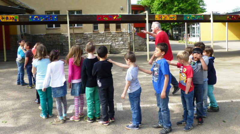 15 Kinder stehen im Halbkreis und machen eine Vertrauensübung.