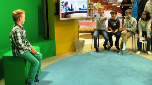 Ein Junge sitzt im WDR Kinderstudio vor einem Greenscreen.
