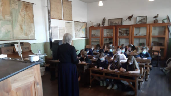 Die Kinder einer Klasse sitzen im Schulmuseum und schreiben auf Schiefertafeln.